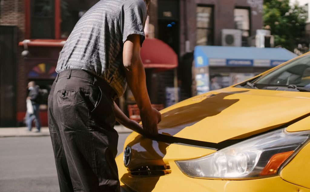 Ethnic driver opening taxi hood on street